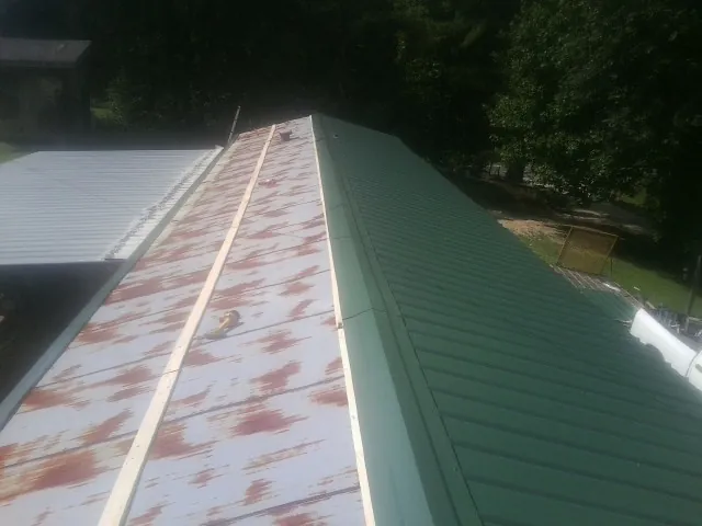 Old rusted panels beside newly installed green metal roofing — Wind Damage Roof Repair by Roofing Brothers in Piney Flats