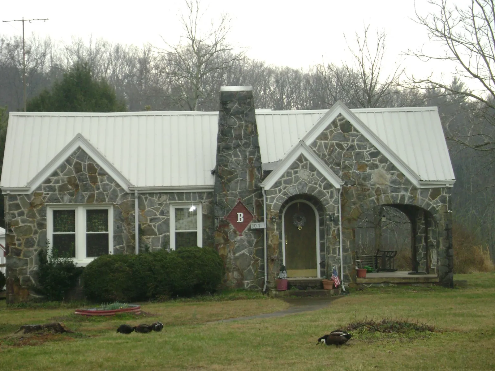 White metal roof on a stone cottage with steep gables in Piney Flats