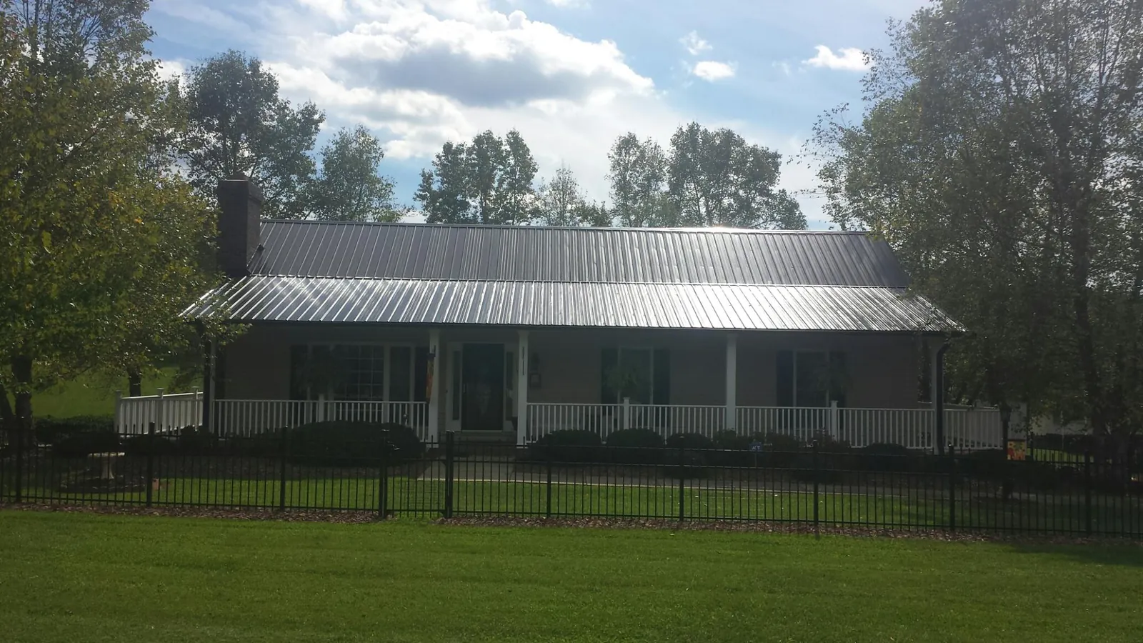 Gray metal roof on a brick ranch with a full width front porch — Gutter Guard Installation work by our crew in Piney Flats