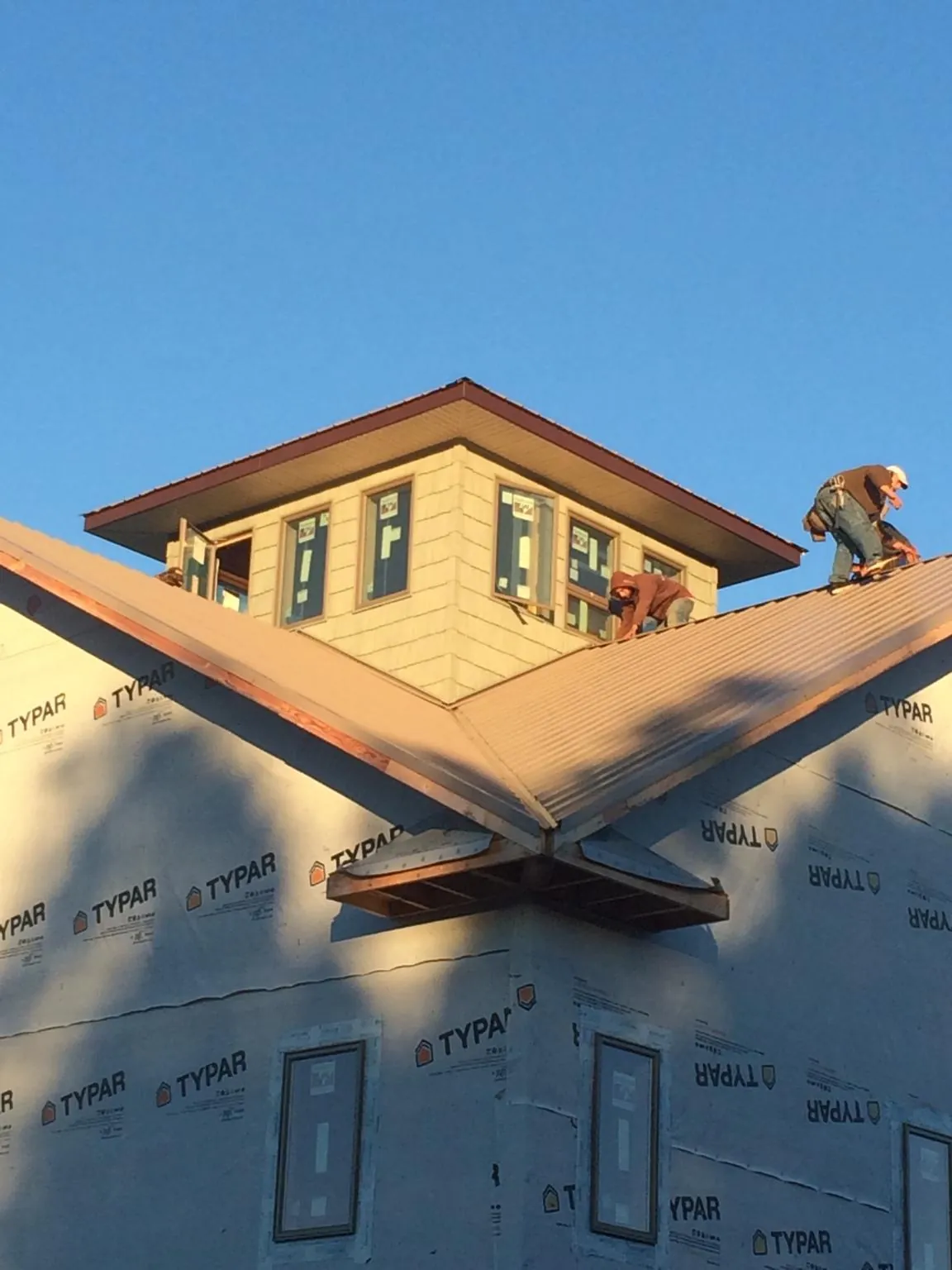 Roofers working around a rooftop cupola on a new metal roof at sunset — Roof Waterproofing in Piney Flats by Roofing Brothers